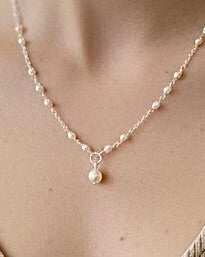 Close-up of bride wearing Amélie pearl necklace with delicate rice pearl spacing and central pearl drop in gold filled or sterling silver