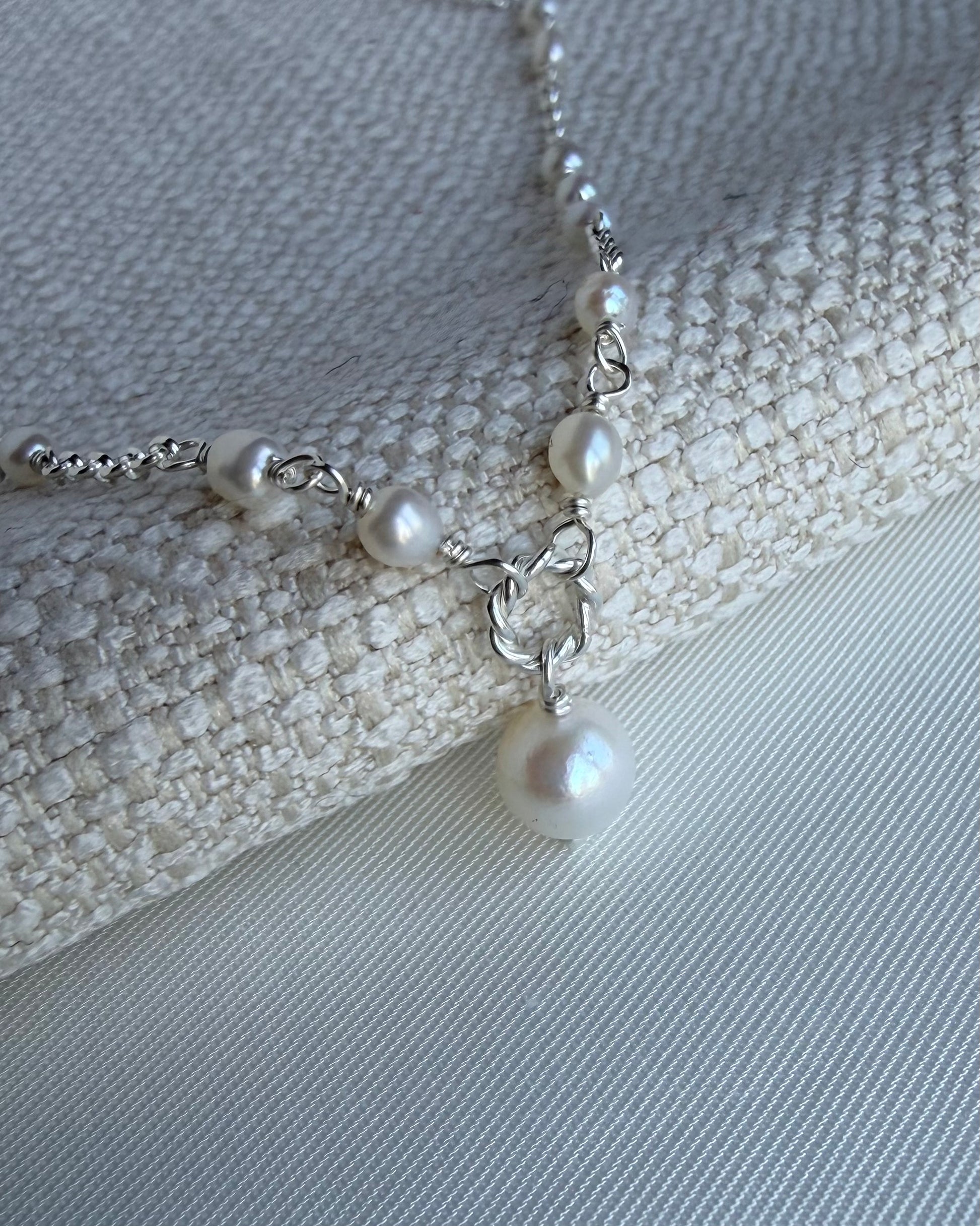 Close-up of Amélie pearl necklace with delicate rice pearl spacing and central pearl drop in gold filled or sterling silver