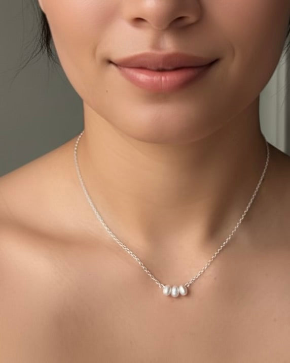 Minimalist pearl necklace featuring three dangling freshwater pearls on a fine chain in sterling silver or gold filled, resting around the collarbones.