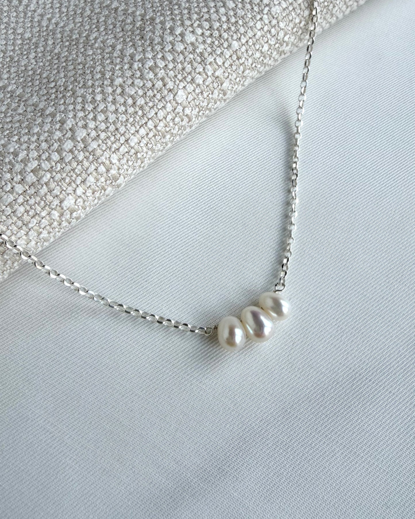Minimalist pearl necklace featuring three dangling freshwater pearls on a fine chain in sterling silver or gold filled, resting around the collarbones.